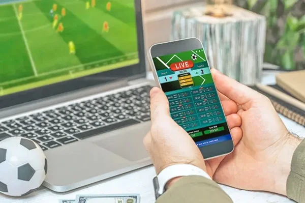 Persona realizando una apuesta deportiva mientras mira un partido en su notebook